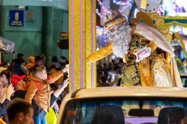 El Rey Melchor recoge la carta de un niño durante la Cabalgata en la calle Capitán Quesada