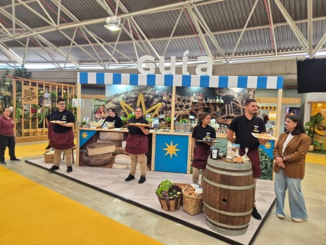 La concejala de Turismo y Sector Primario junto al alumnado trabajador del PFAE El Jilorio delante del stand de Guía